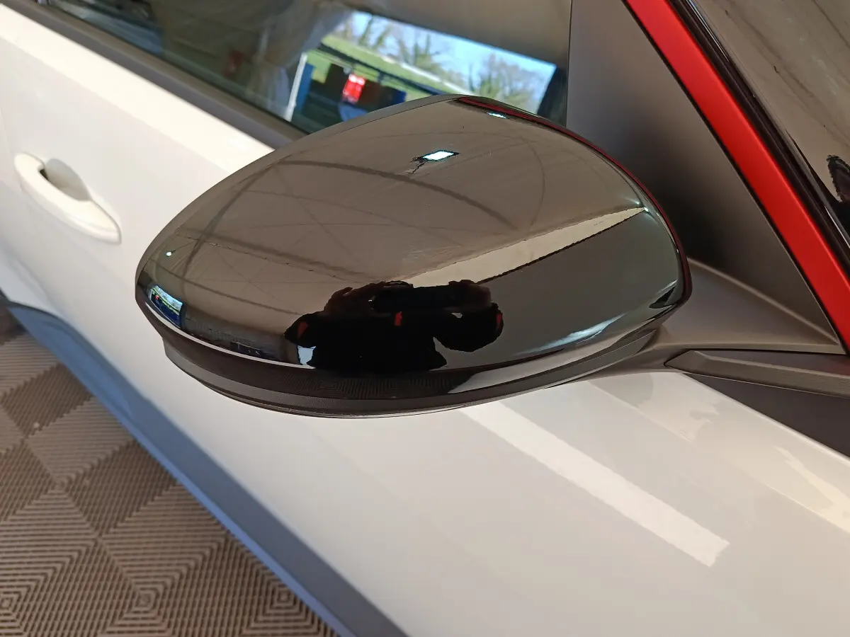 Rétroviseur extérieur noir en gros plan sur côté gauche d’une Renault R5 blanche 2025 électrique.