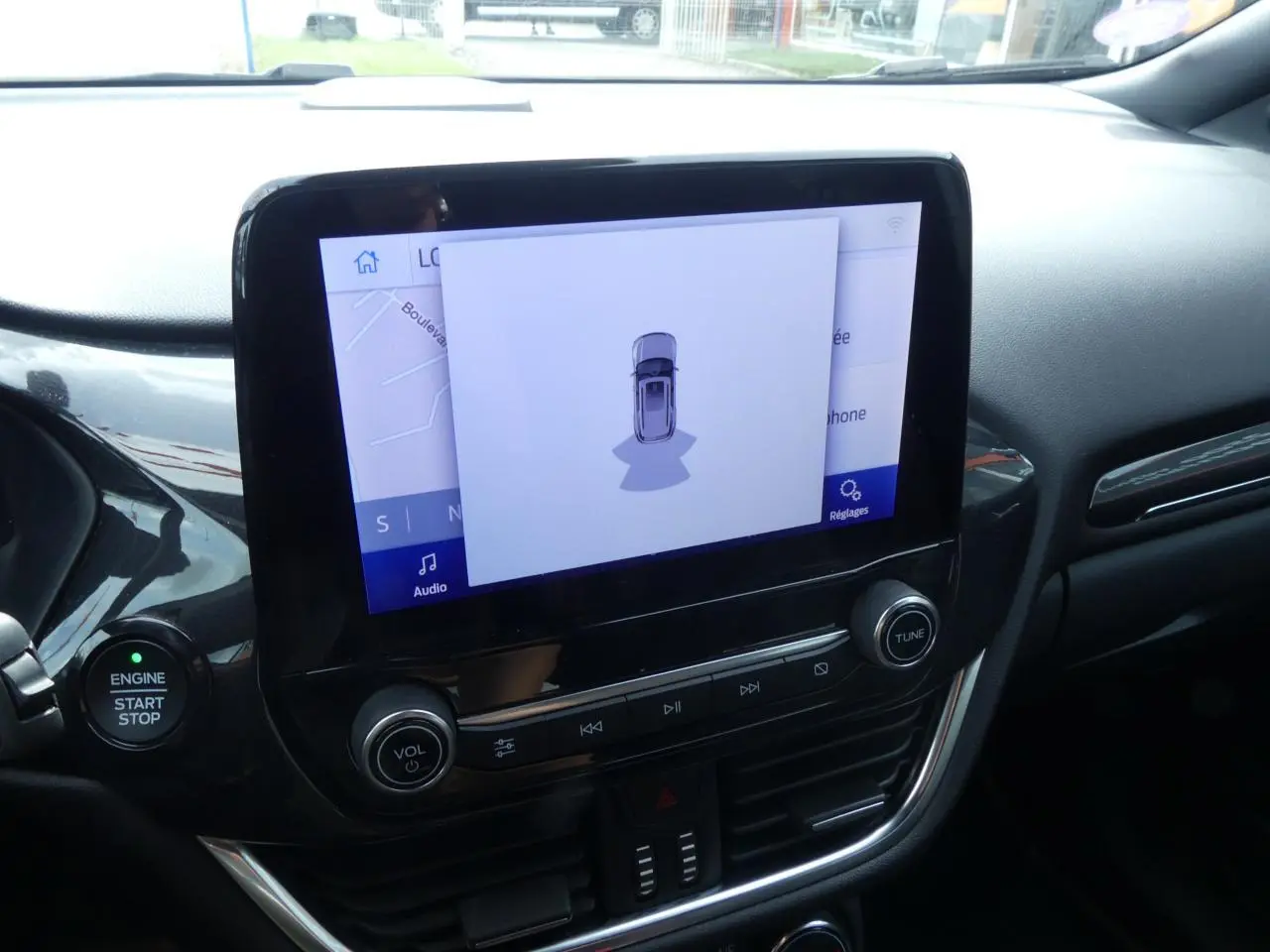 Vue rapprochée de l’écran tactile central et du bouton démarrage du Ford Puma blanc, intérieur noir avec finitions brillantes.