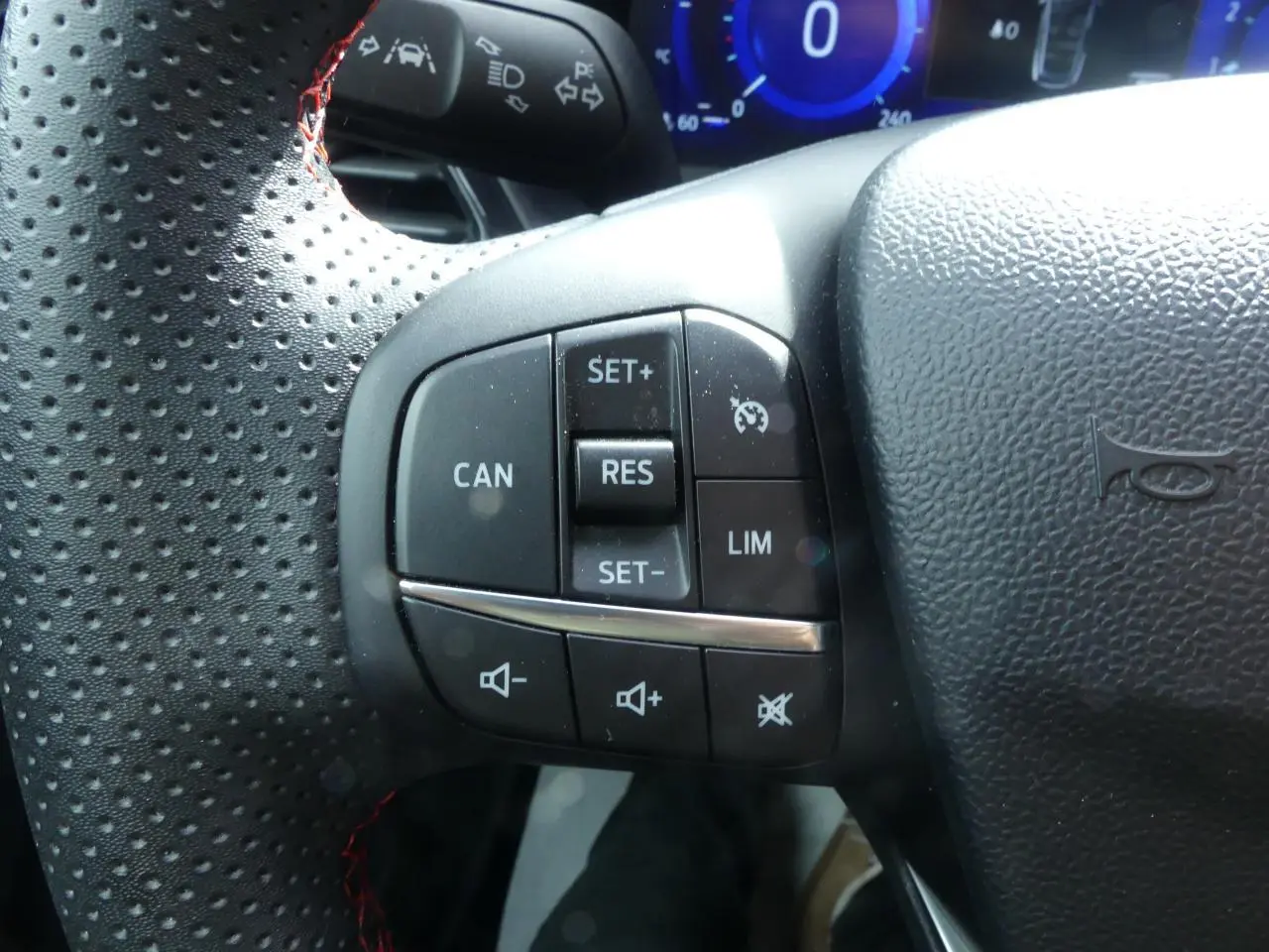 Gros plan sur les commandes de régulateur de vitesse et volume du volant perforé noir du Ford Puma blanc 2020 ST Line.