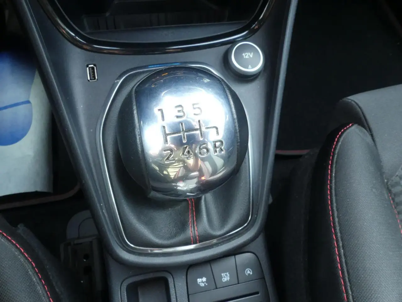 Gros plan sur levier de vitesses manuel chromé avec surpiqûres rouges sur sellerie noire du Ford Puma blanc ST Line.