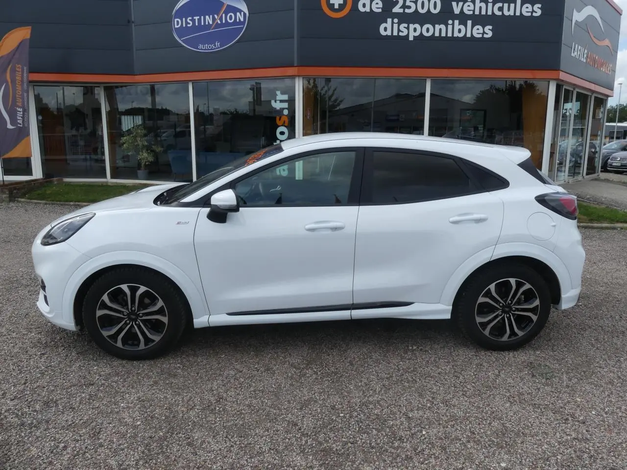 Vue latérale droite d'un Ford Puma blanc avec vitres arrière surteintées et jantes alliage noires.
