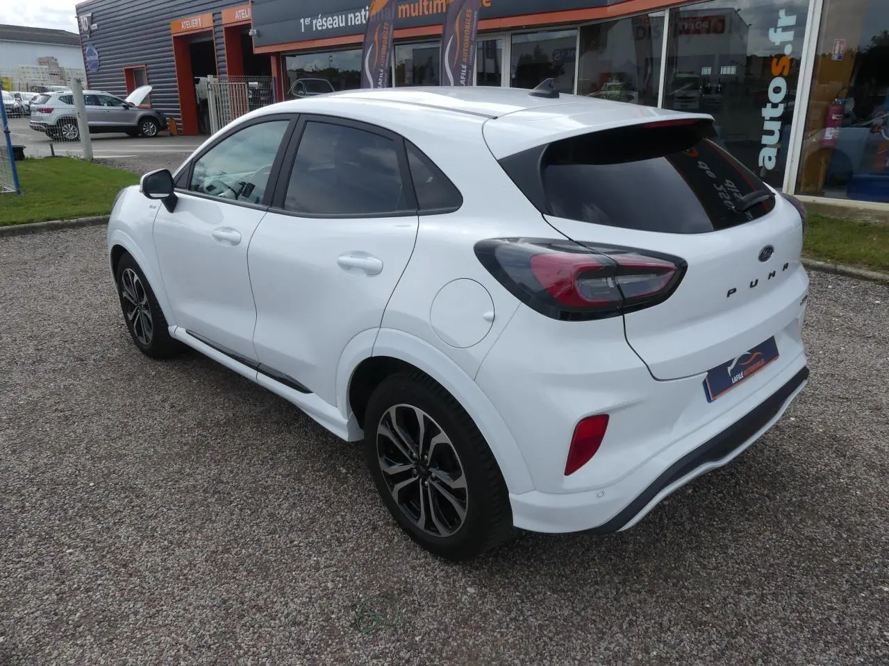 Vue 3/4 arrière droite d'un Ford Puma blanc avec vitres arrière surteintées et jantes alliage noires.