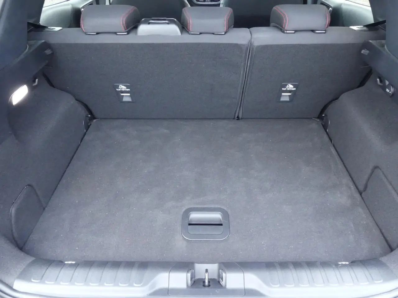 Coffre spacieux noir du Ford Puma blanc 2020, vue intérieure arrière avec banquette rabattue et fixations Isofix visibles.