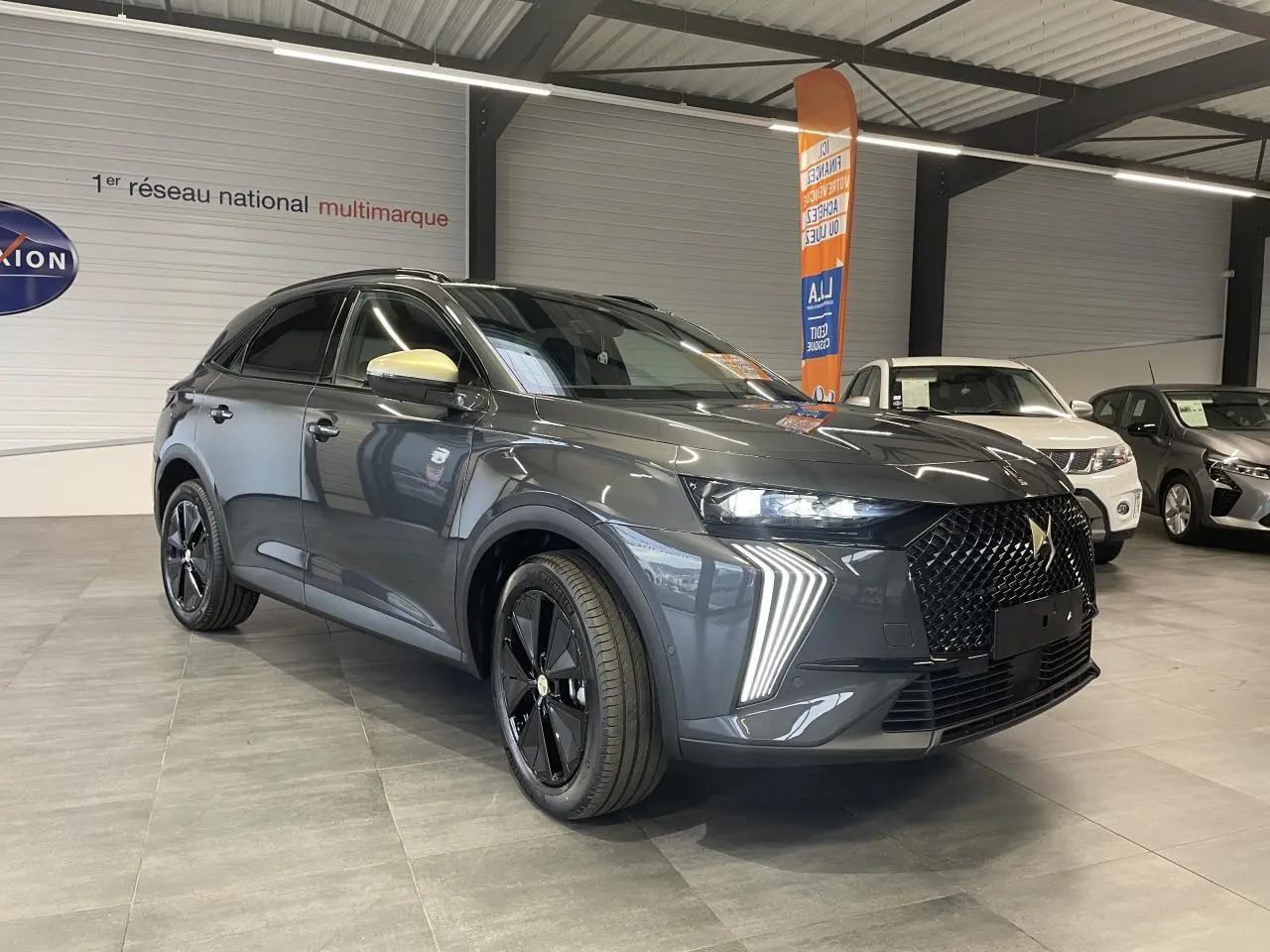 DS7 Crossback gris titanium en 3/4 avant droit, avec calandre noire brillante et feux LED distinctifs en forme de flèche.