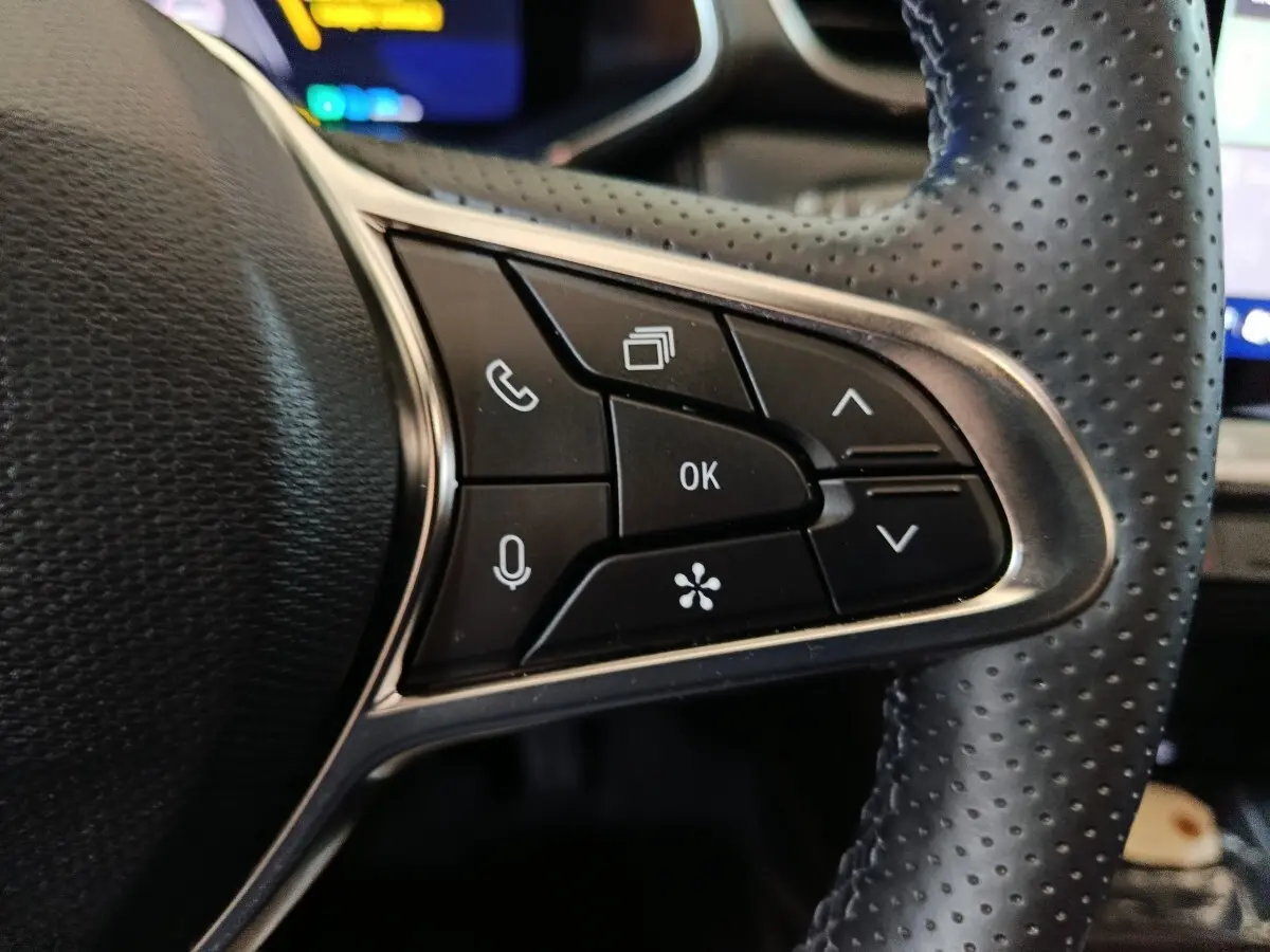 Gros plan sur les commandes multifonctions noires du volant perforé côté gauche du Renault Symbioz bleu 2025.