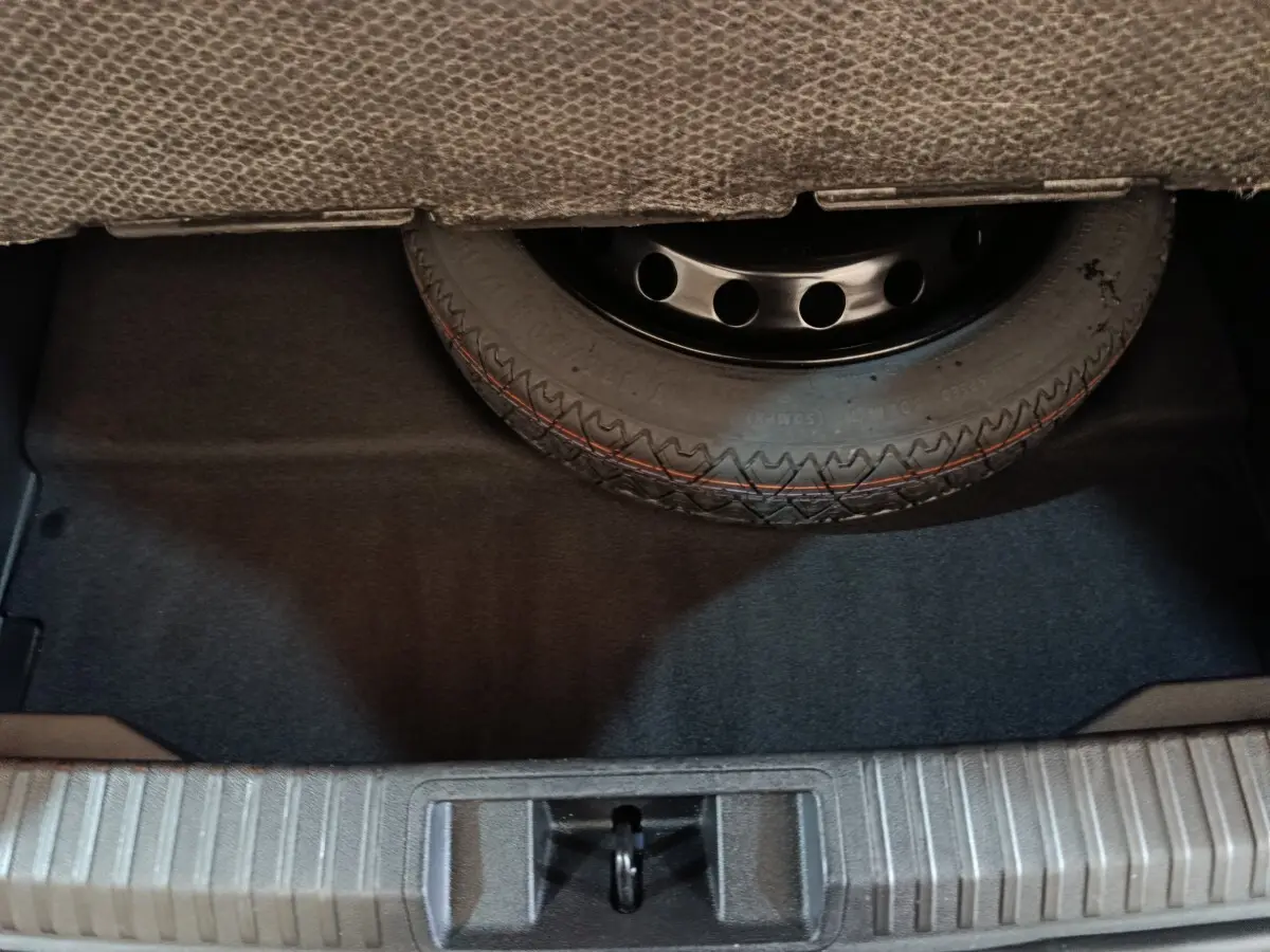 Vue rapprochée du coffre montrant la roue de secours sous la moquette, sans visibilité du véhicule Renault Symbioz.