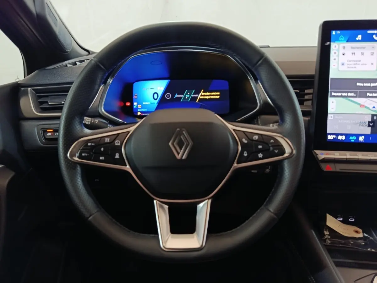 Vue centrée sur le volant noir du Renault SYMBIOZ 2025 avec tableau de bord numérique et écran tactile latéral.