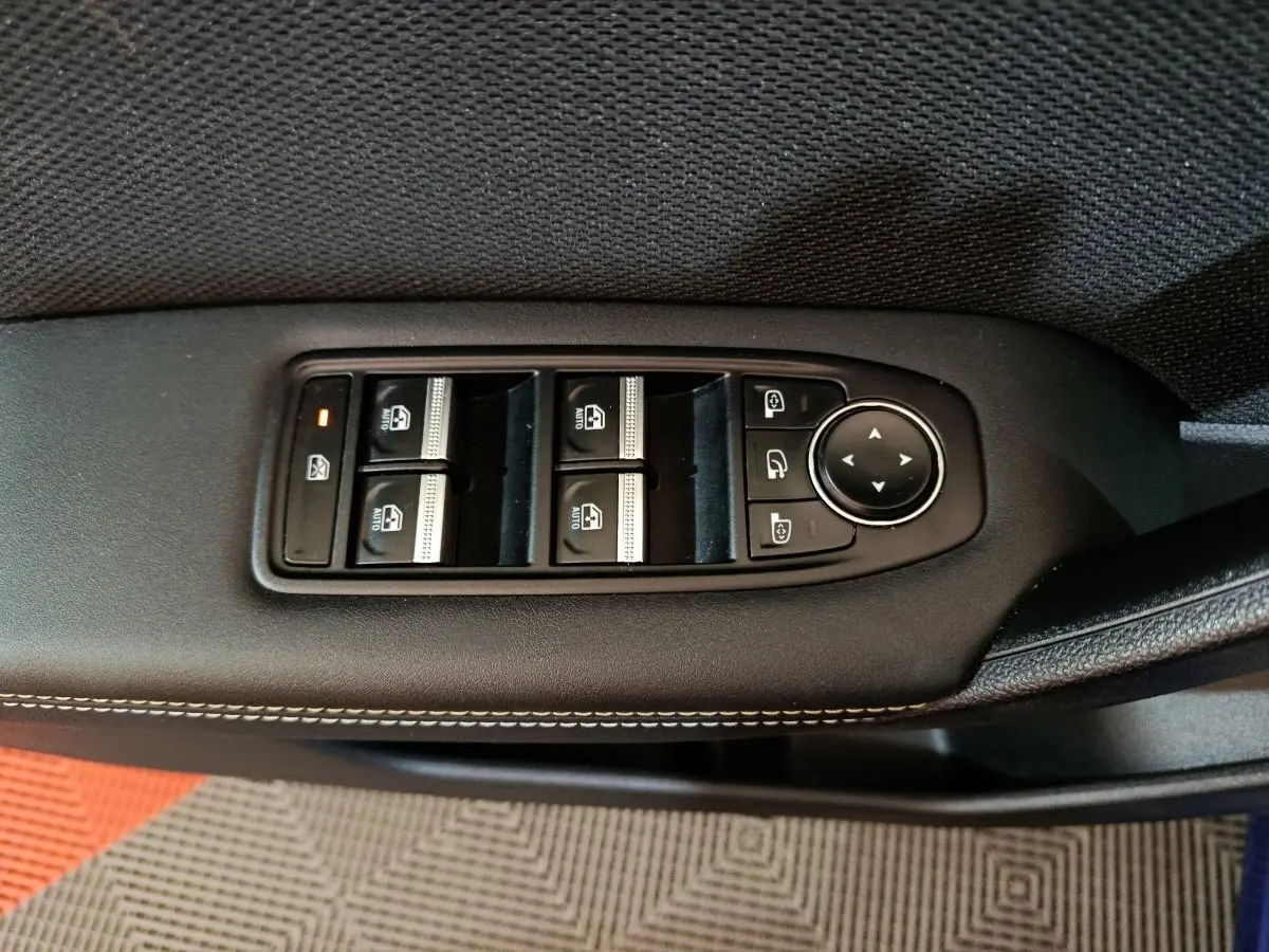 Détail des commandes des vitres et rétroviseurs sur la porte côté conducteur d'une Renault Symbioz bleu.