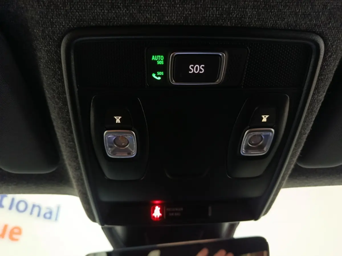 Vue en contre-plongée du panneau de commande au plafond avec bouton SOS éclairé dans un Renault Symbioz bleu.