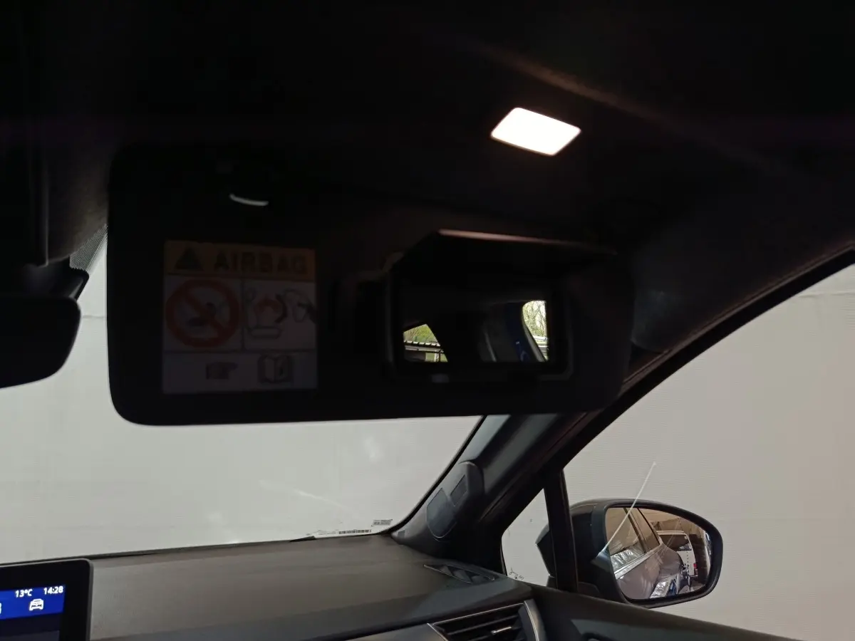 Intérieur côté conducteur du Renault Symbioz bleu, avec pare-soleil rabattu et miroir éclairé visible.