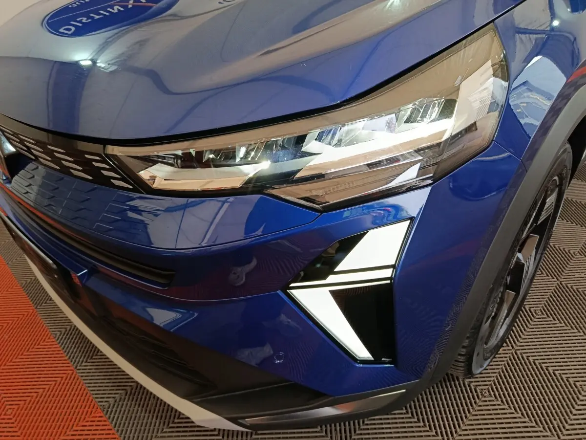Gros plan sur l'avant droit bleu du Renault SYMBIOZ 2025, mettant en valeur ses phares LED et feux diurnes en forme de flèche.