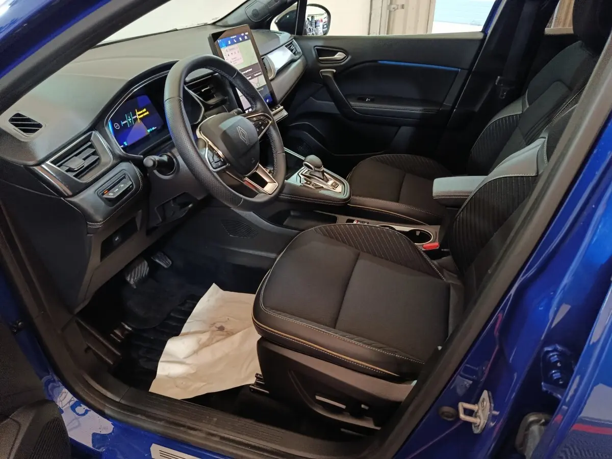 Vue intérieure côté conducteur de la Renault SYMBIOZ bleu, avec tableau de bord digital et écran tactile central.