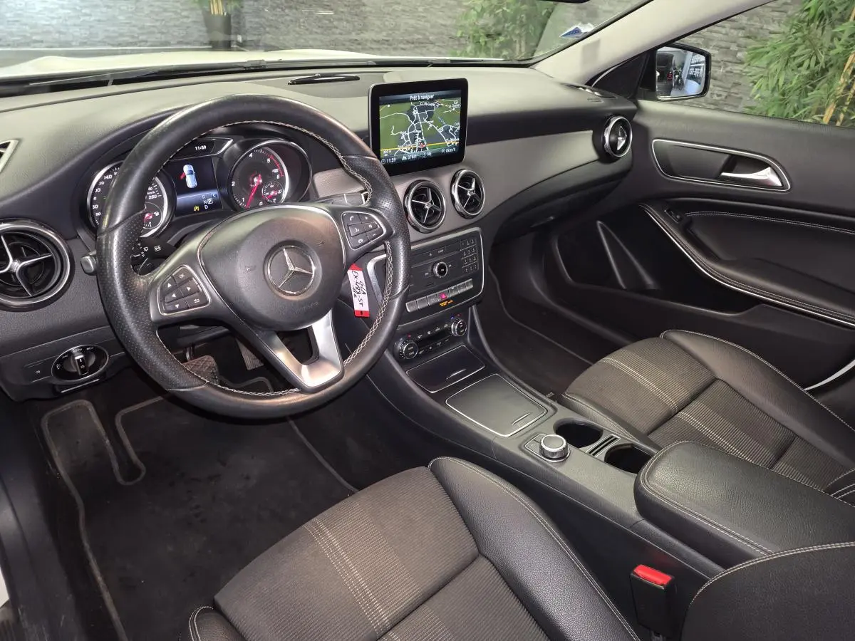 Vue intérieure côté conducteur du Mercedes GLA 220 d 2017, tableau de bord noir avec écran central et volant cuir multifonctions.
