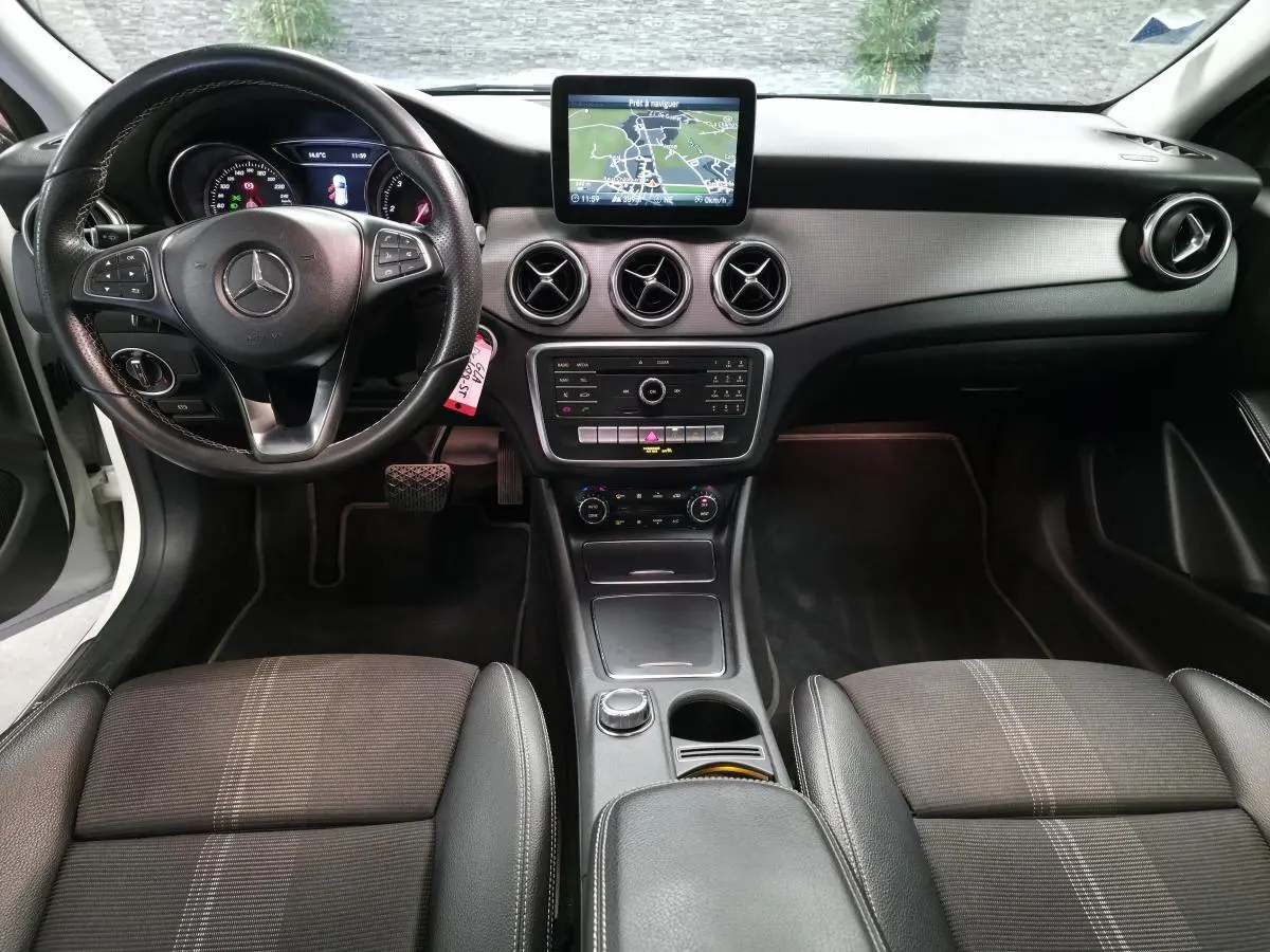 Vue intérieure avant de la Mercedes GLA 220 d 2017, tableau de bord noir avec écran central et volant multifonctions.