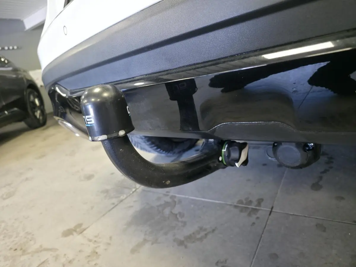 Gros plan sur l'attelage noir démontable sous le pare-chocs arrière blanc de la Mercedes GLA 220 d Sensation 4-Matic.