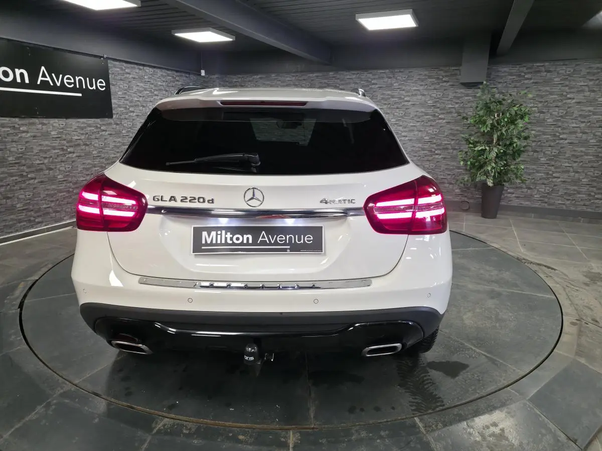Vue arrière d'un Mercedes GLA 220 d blanc avec feux allumés, attelage démontable et logo 4MATIC visible.