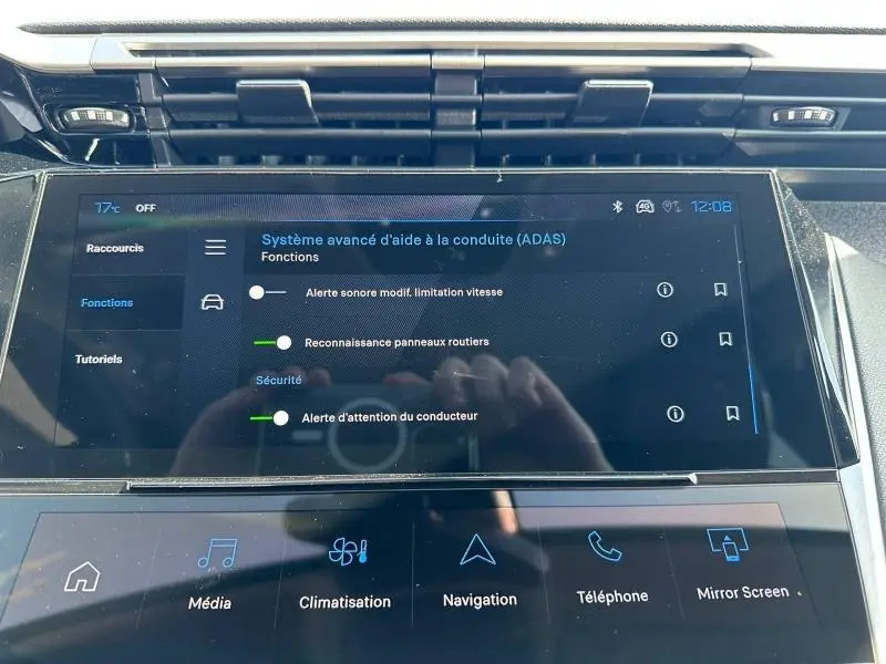 Gros plan sur l'écran tactile central du tableau de bord de la Peugeot 308 bleu, affichant les aides à la conduite.