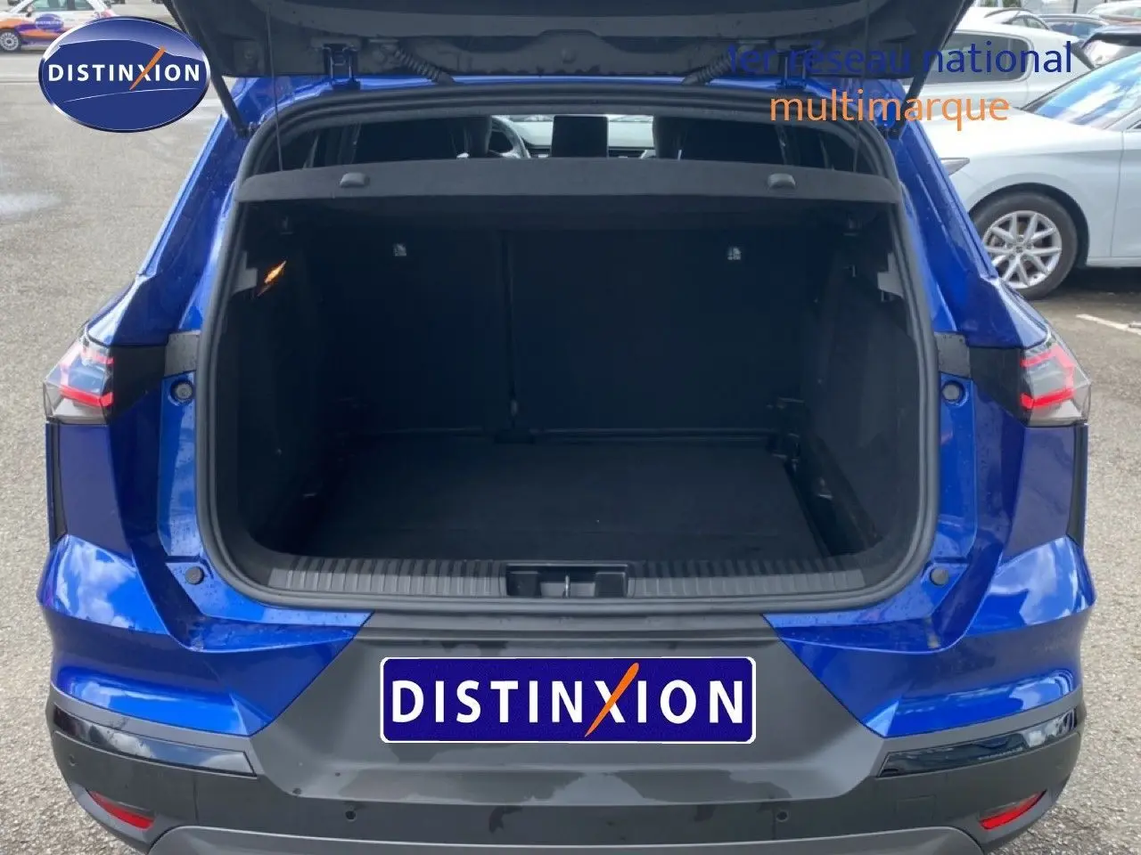 Vue arrière d'un Renault Symbioz E-Tech Full Hybrid 145ch Esprit Alpine bleu Iron Metal avec coffre ouvert sur parking.
