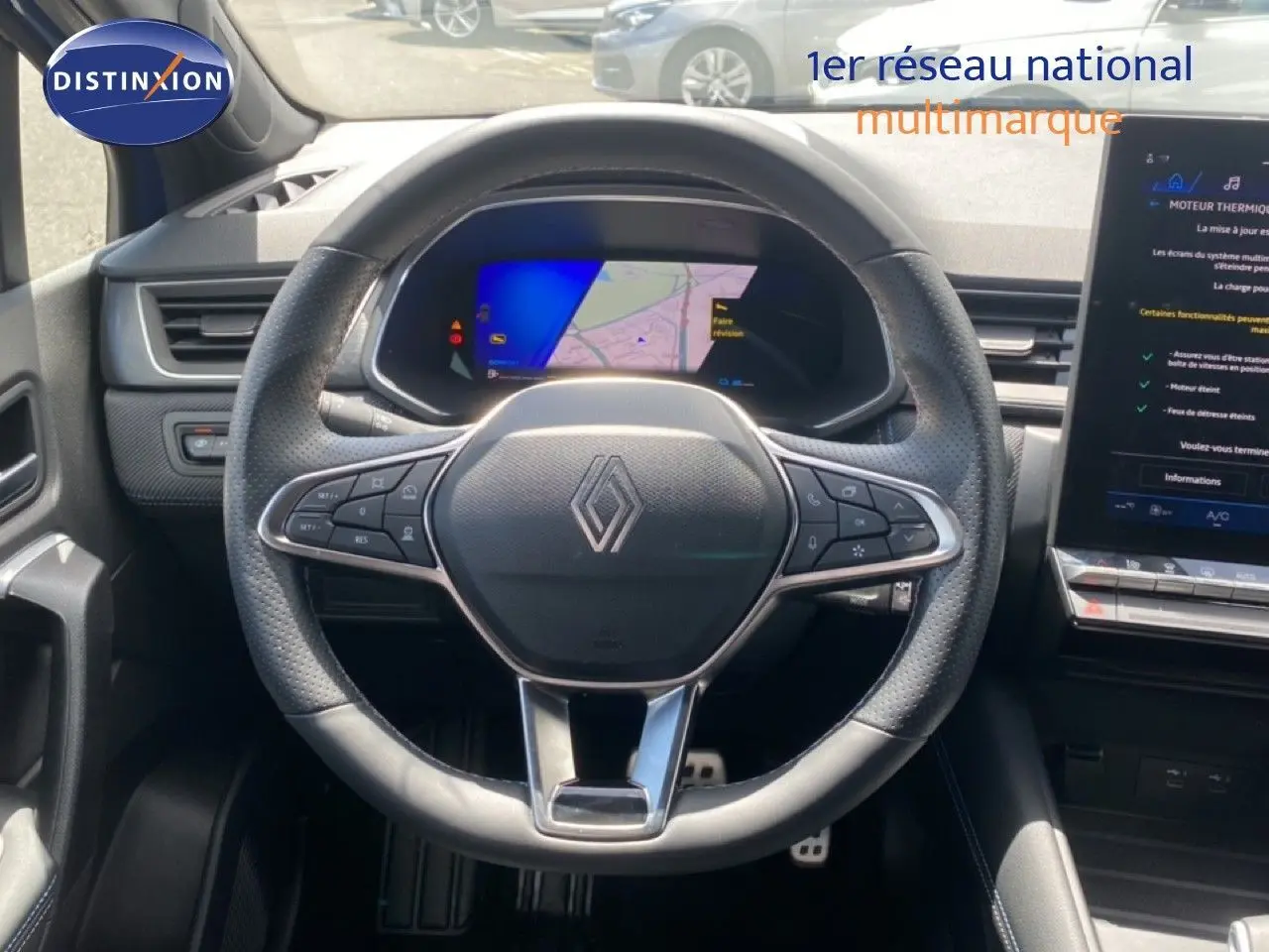 Vue intérieure centrée sur le volant perforé Renault Symbioz 2025 avec tableau de bord numérique et écran tactile adjacent.