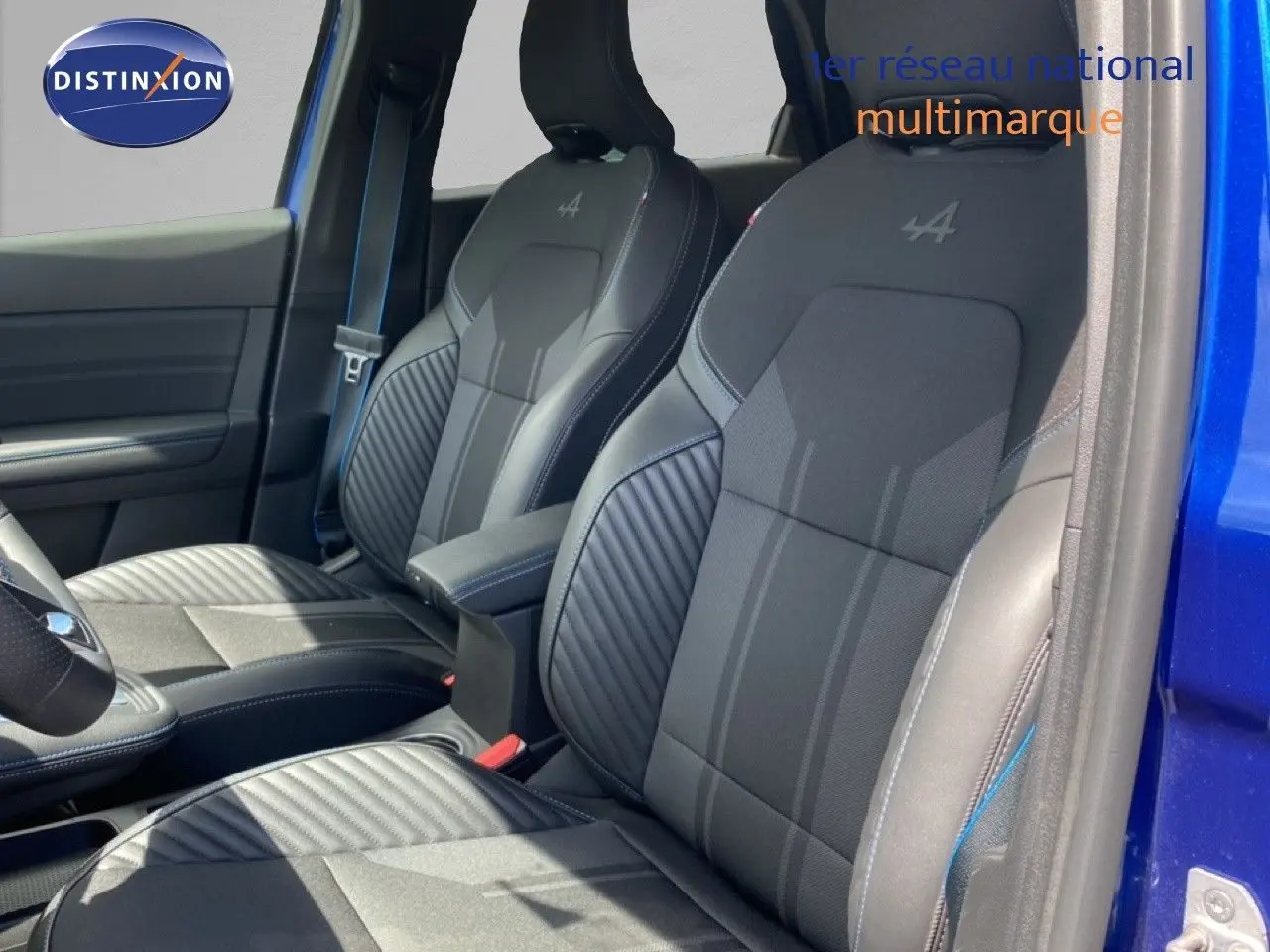 Vue intérieure côté conducteur montrant les sièges noirs avec logo Alpine sur une Renault Symbioz bleu iron metal.