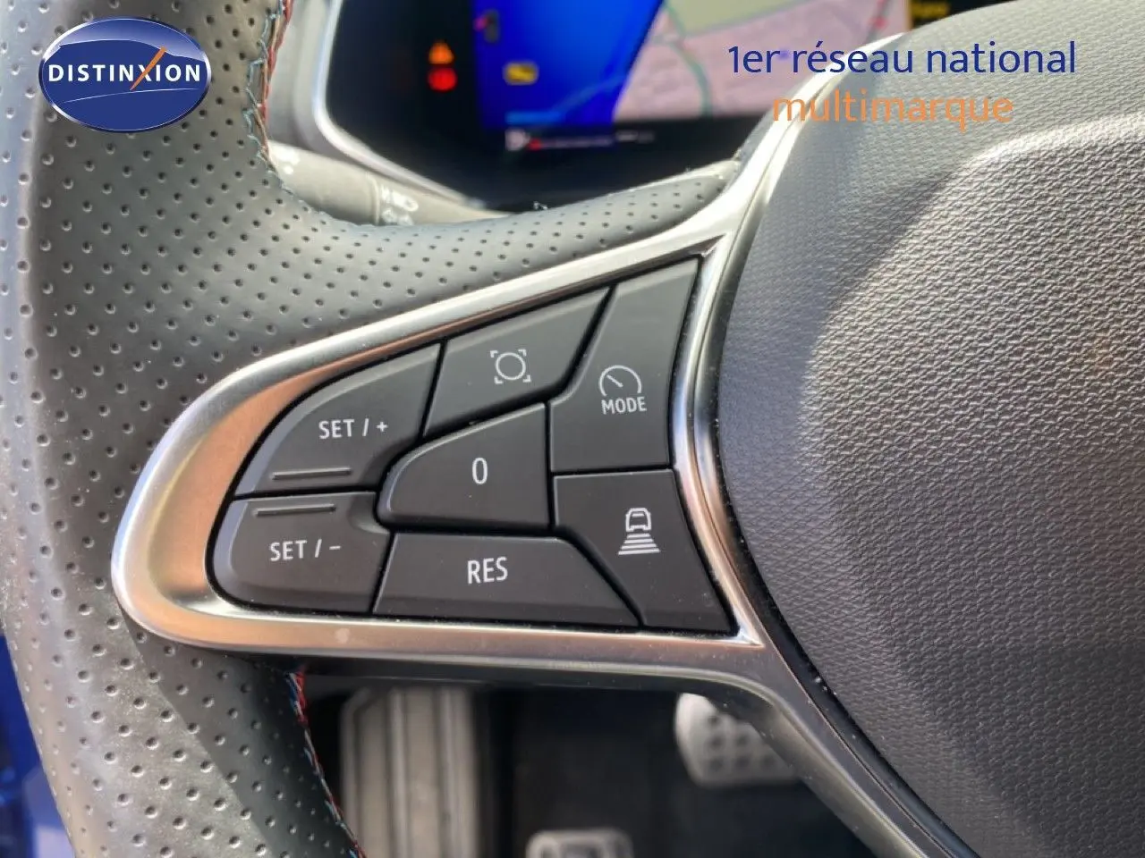 Gros plan sur les commandes au volant côté gauche d’une Renault Symbioz bleu Iron Metal, affichage numérique en arrière-plan.