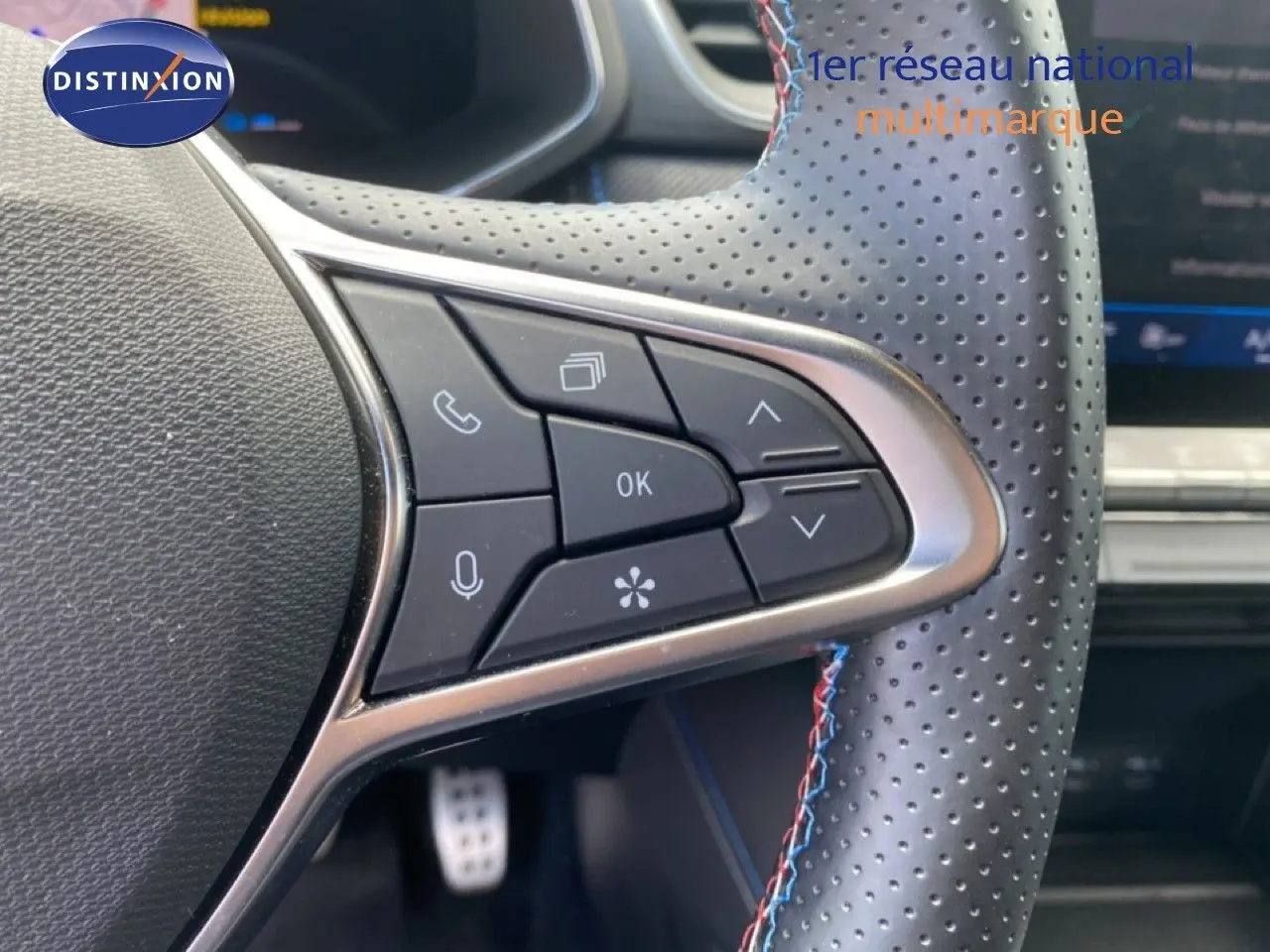 Gros plan sur les commandes au volant côté gauche du Renault Symbioz E-Tech Full Hybrid 2025 avec surpiqûres tricolores.