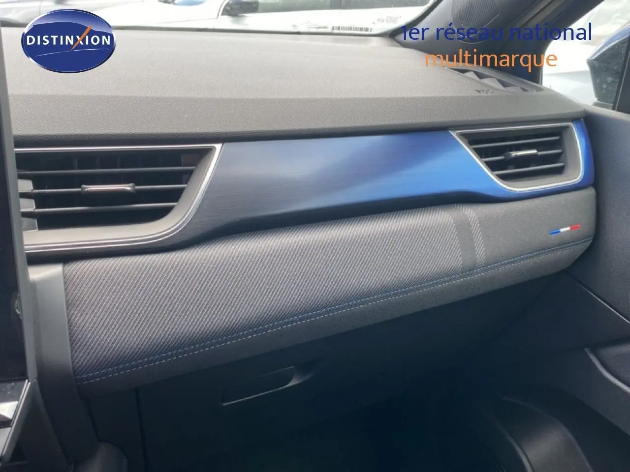 Détail de la planche de bord côté passager du Renault Symbioz 2025 avec insert bleu Iron Metal et surpiqûres bleues.