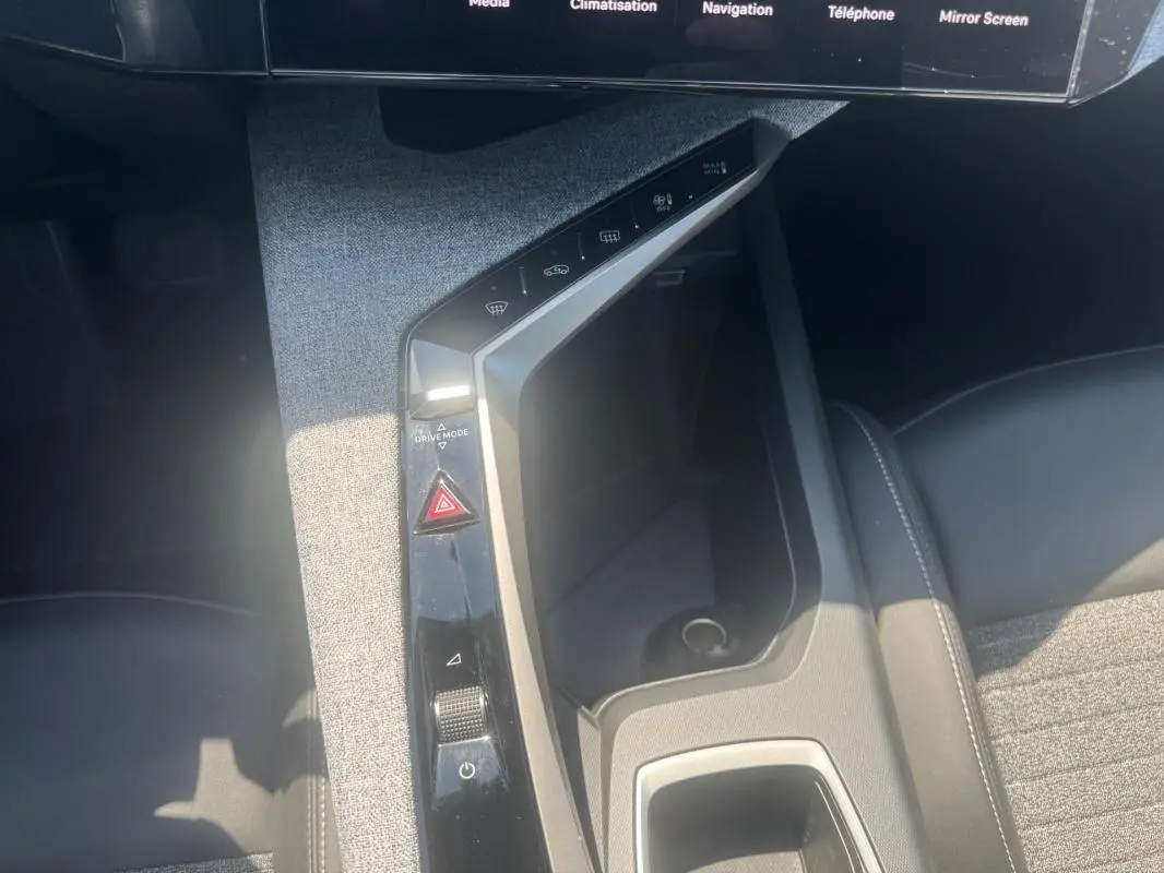 Vue plongeante sur la console centrale grise du Peugeot 5008 Hybrid 2025 avec commandes tactiles et rangement intégré.
