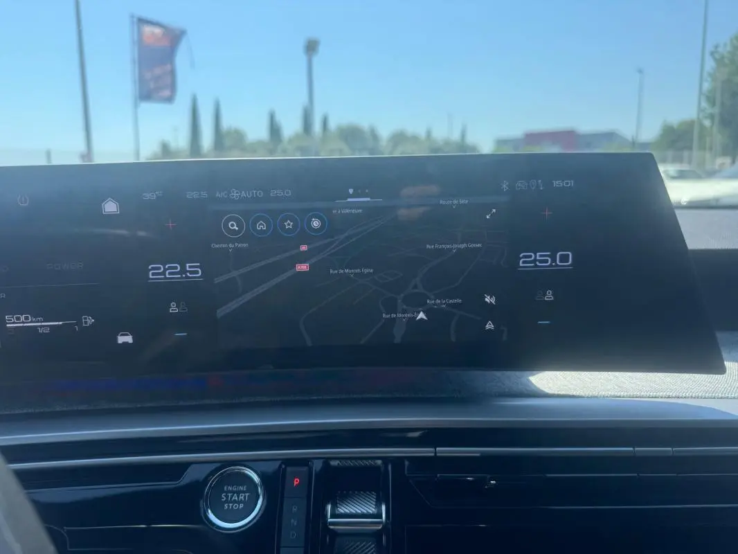 Tableau de bord numérique du Peugeot 5008 Hybrid 2025 avec écran central affichant la navigation et commandes climatisation.