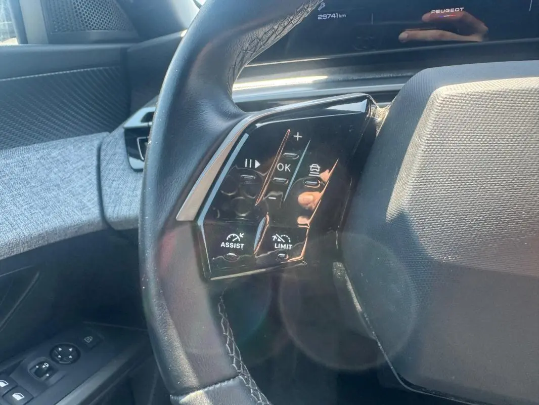 Gros plan sur le volant côté gauche du Peugeot 5008 gris 2025 Hybrid avec commandes d’assistance et limitation de vitesse.