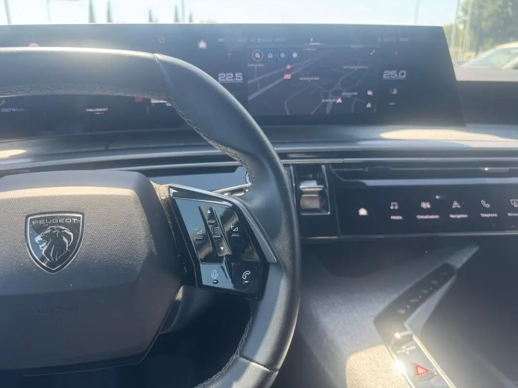 Vue rapprochée du tableau de bord et volant du Peugeot 5008 Hybrid gris 2025, avec écran tactile et commandes au volant.