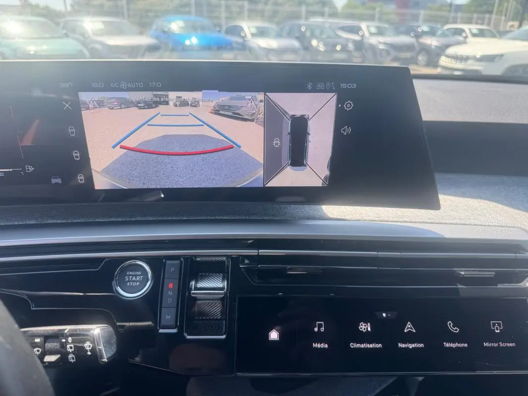 Vue intérieure du tableau de bord du Peugeot 5008 Hybrid gris, avec écran multimédia affichant la caméra de recul et les commandes tactiles.