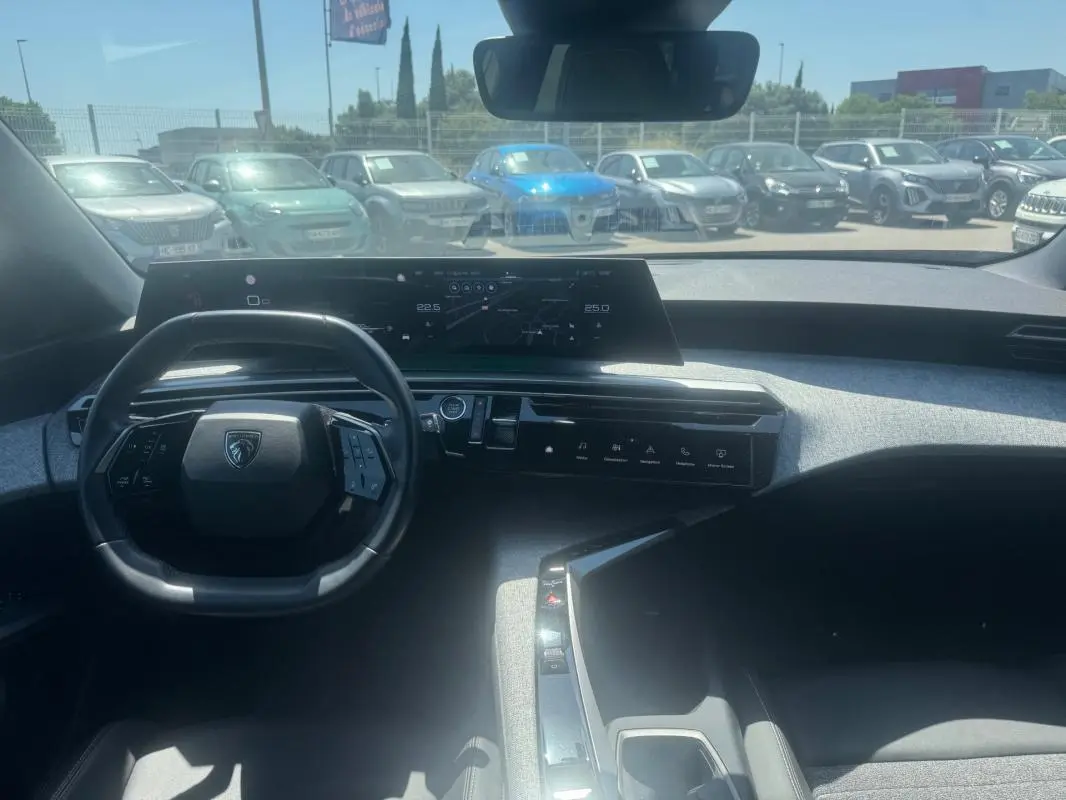 Vue intérieure avant du Peugeot 5008 Hybrid gris 2025, avec tableau de bord numérique et volant compact.