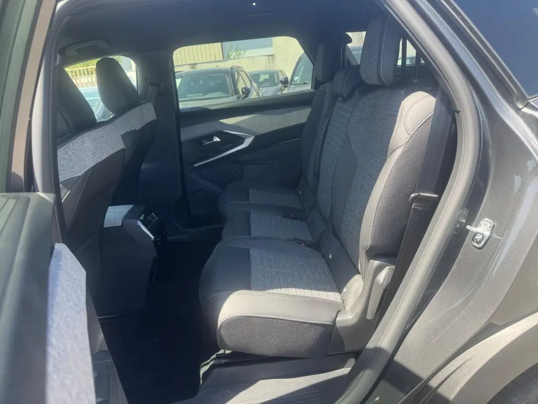 Vue intérieure côté droit des sièges arrière du Peugeot 5008 gris hybride 2025, avec sellerie tissu et cuir bicolore.