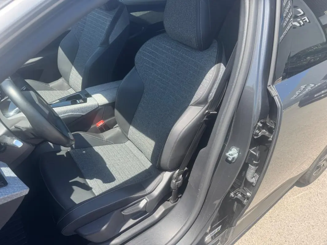 Vue intérieure côté conducteur du Peugeot 5008 Hybrid gris 2025, mettant en valeur les sièges tissu et cuir bicolores.