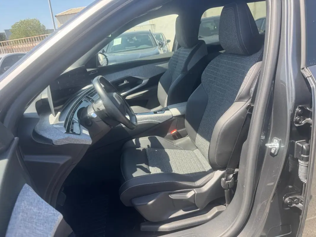 Vue intérieure côté conducteur du Peugeot 5008 Hybrid gris 2025, mettant en valeur les sièges bi-matière et le tableau de bord moderne.