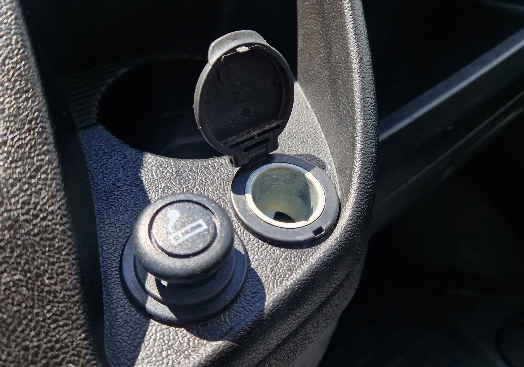 Gros plan sur la prise allume-cigare et son cache ouvert dans l'habitacle du Citroën Jumper blanc.