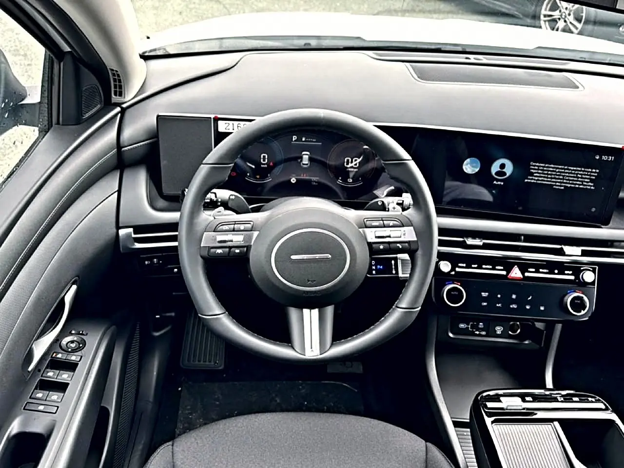 Intérieur noir du Hyundai Tucson 2026, vue frontale du volant cuir multifonction et tableau de bord digital.