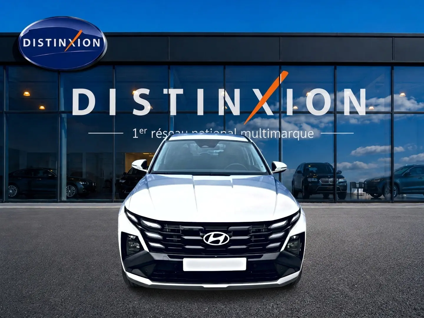 Vue de face du Hyundai Tucson blanc 2026 avec calandre noire distinctive devant une vitrine Distinxion.