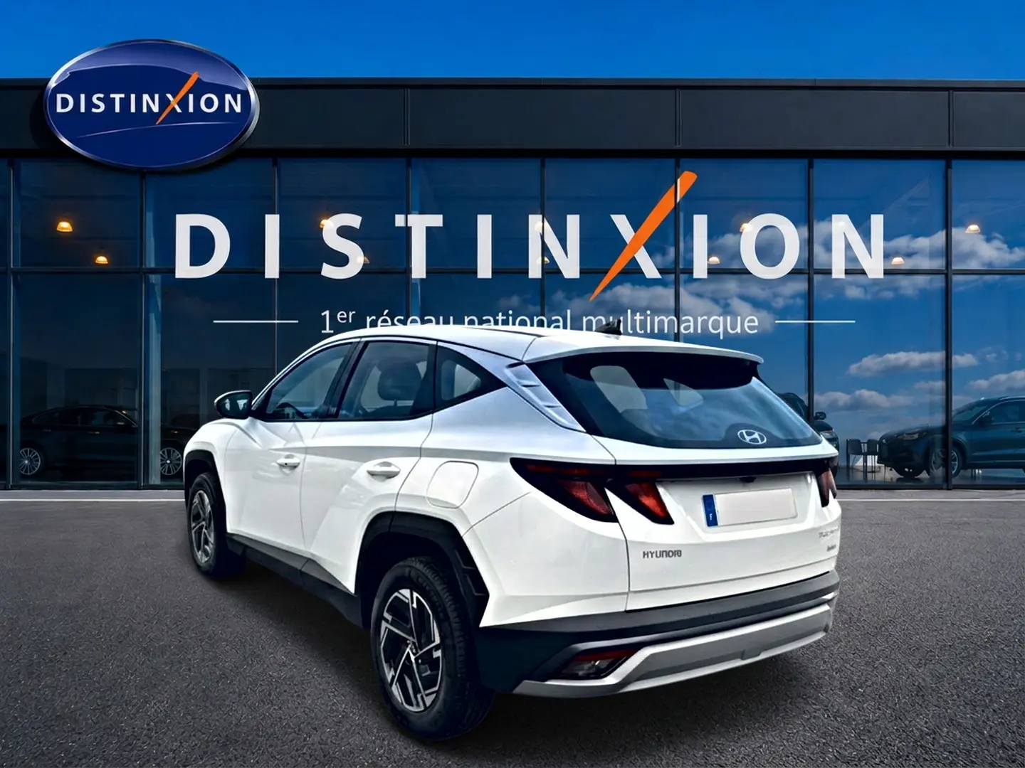 Vue 3/4 arrière droite du Hyundai Tucson blanc 2026 hybride, avec jantes alliage et feux arrière LED distinctifs.