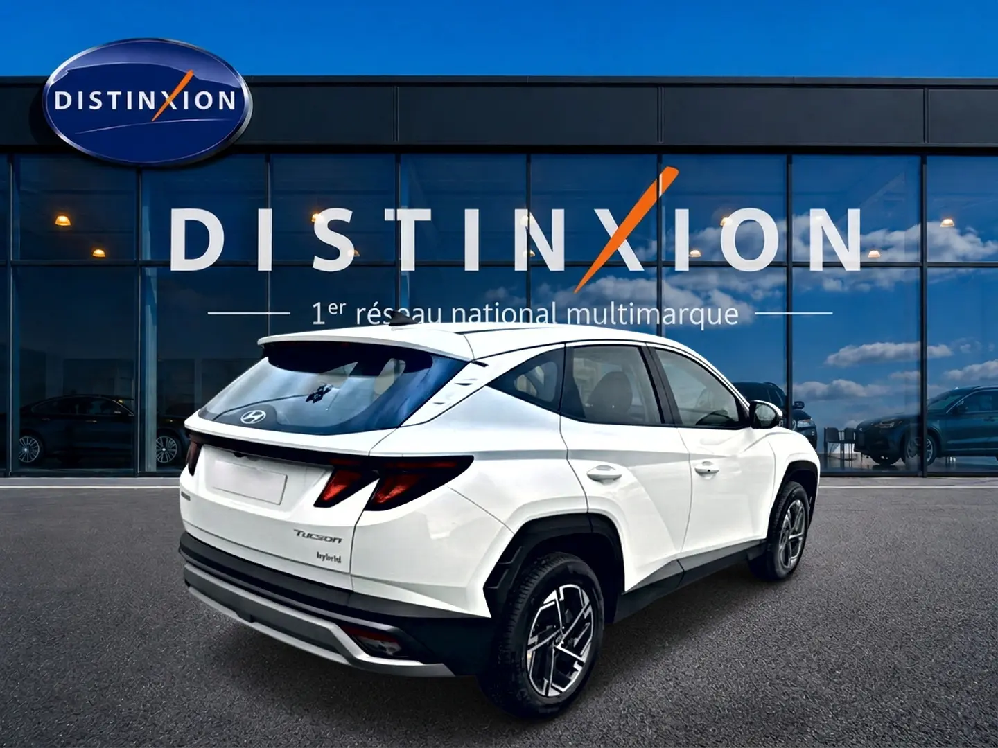 Vue 3/4 arrière droite d'un Hyundai Tucson blanc hybride 2026 avec jantes alliage et feux arrière LED distinctifs.
