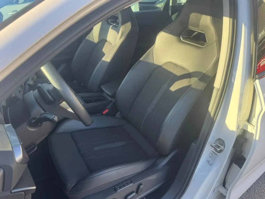Vue intérieure côté conducteur d'une CUPRA Leon Sportstourer blanche 2024, sièges sport en cuir noir avec surpiqûres.