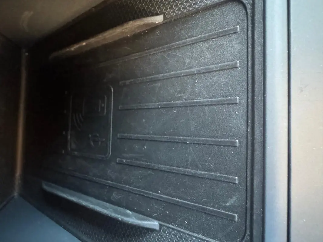 Gros plan sur le tapis de recharge sans fil noir dans l'habitacle du CUPRA Leon Sportstourer blanc 2024.