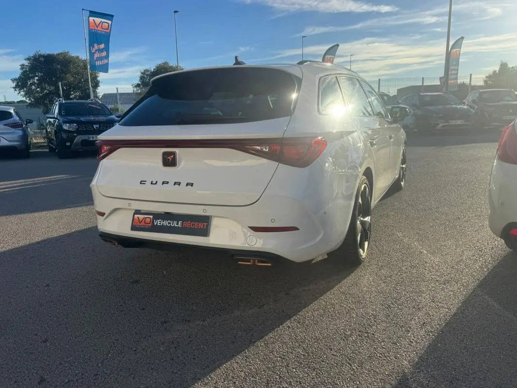 Vue 3/4 arrière droite d'une CUPRA Leon Sportstourer blanche 2024 avec feux arrière reliés et double sortie d'échappement.