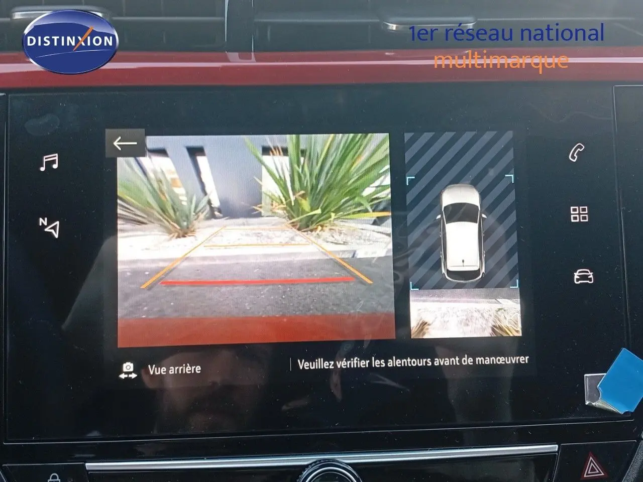 Écran multimédia affichant la caméra de recul et la vue 360° d'une Opel Corsa rouge à toit noir, intérieur moderne.