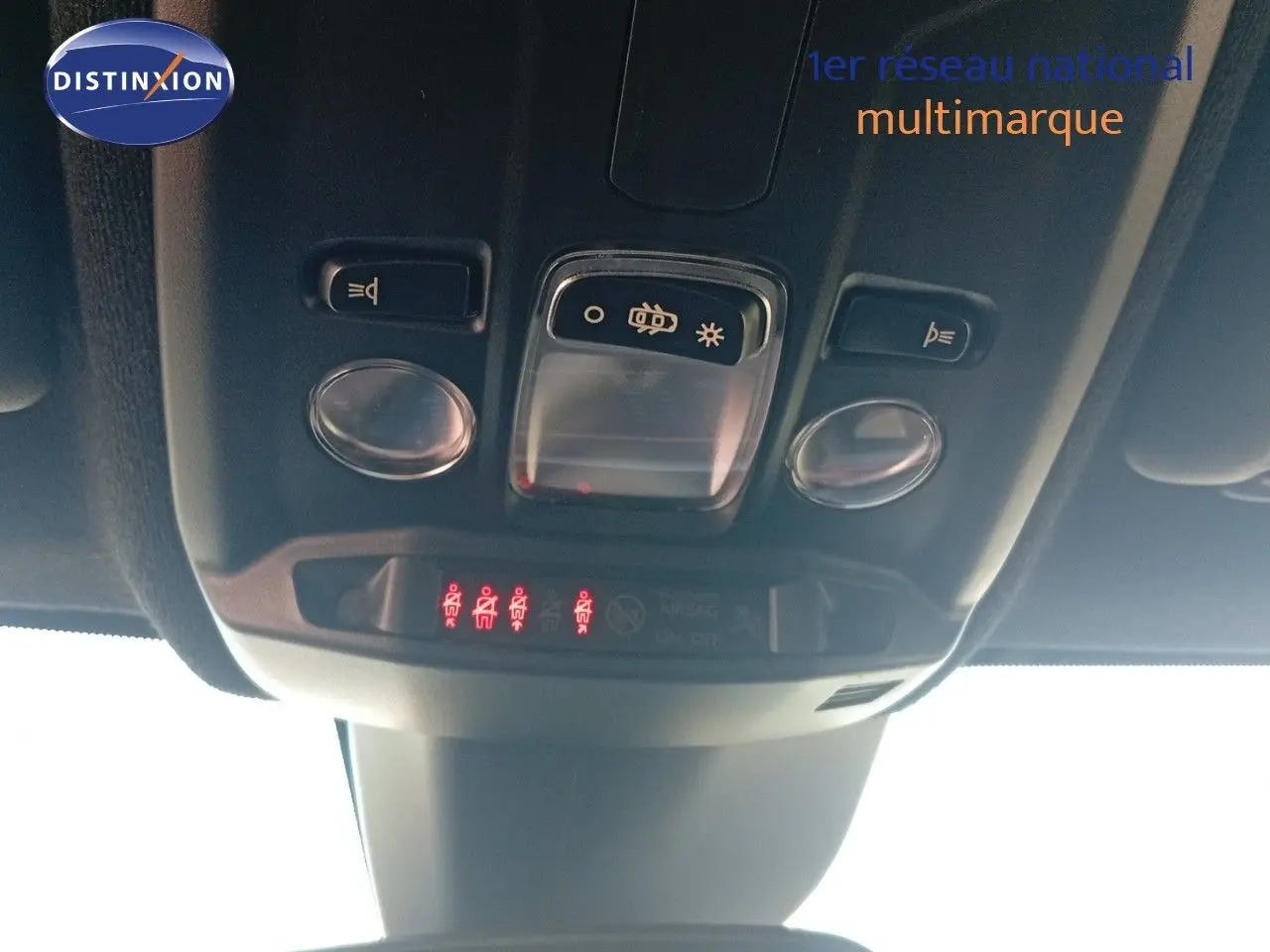 Vue en contre-plongée du plafonnier intérieur de l'Opel Corsa rouge Kardio métal avec toit noir, montrant les commandes d'éclairage.