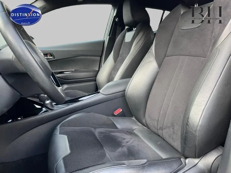 Vue intérieure côté conducteur du Toyota C-HR 122h Collection 2WD 2019, sièges cuir et alcantara noirs avec accoudoir central.