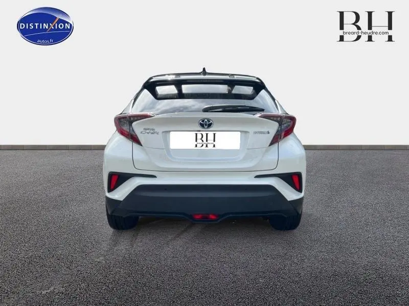 Vue arrière d'un Toyota C-HR 122h Collection 2WD blanc nacré bi-ton avec feux arrière LED et becquet noir.