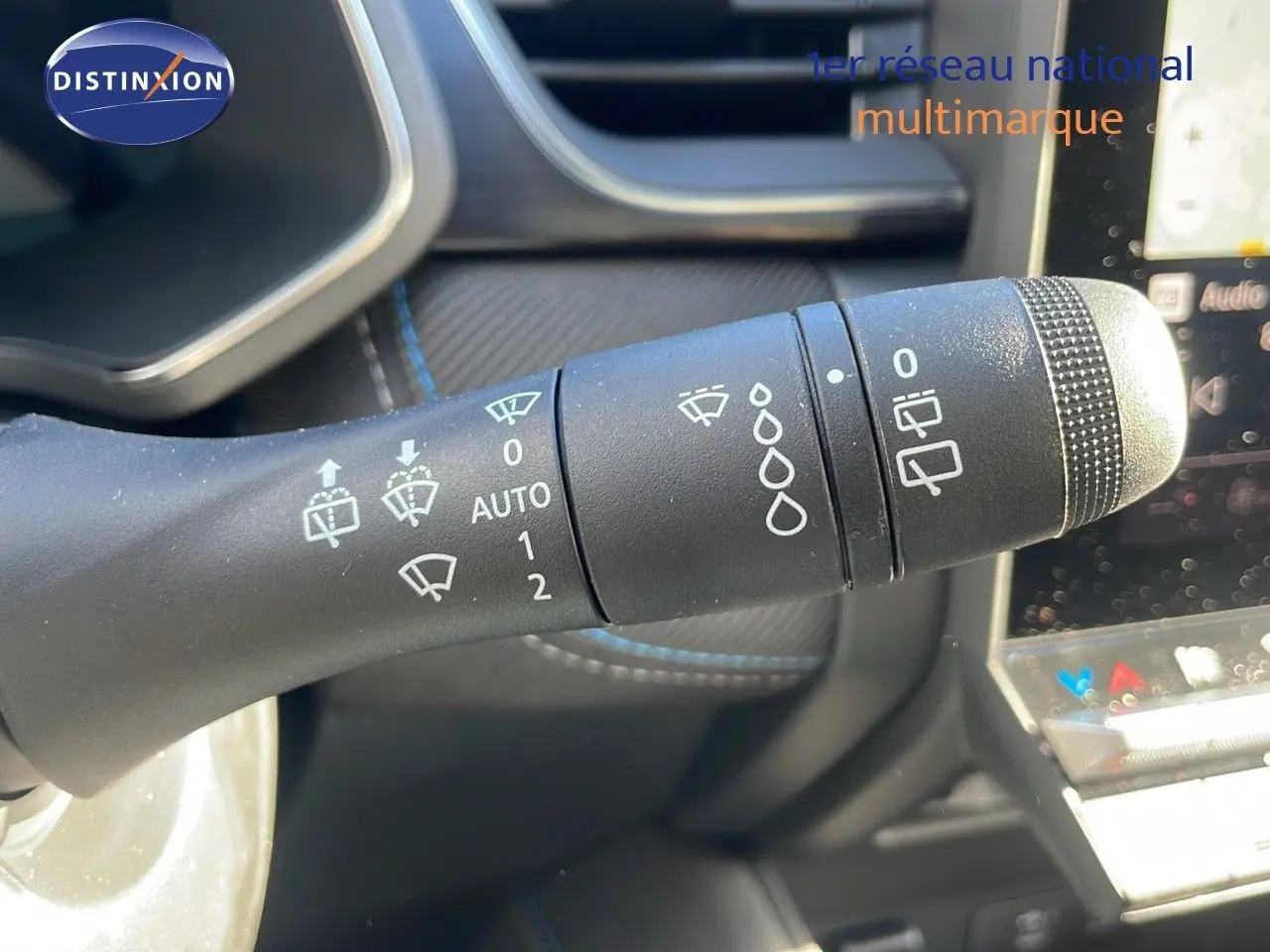 Gros plan sur la commande d'essuie-glace du Renault Captur E-Tech gris rafale avec intérieur noir et coutures bleues.