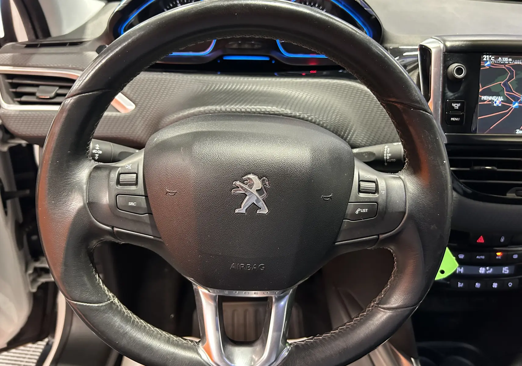 Vue rapprochée du volant cuir noir de la Peugeot 2008 avec logo lion et écran GPS visible à droite.
